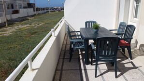 An outdoor patio with a table and chairs, a potted plant, and a view of the sea. - Apartment sunny beach (Peniche)