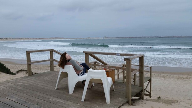 A wooden deck with a white plastic chair and a wooden railing. - Apartment sunny beach (Peniche)