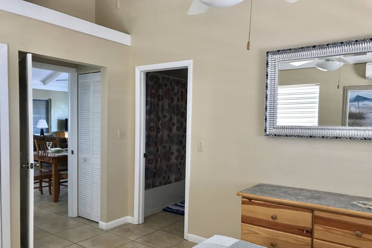 Una habitación con un aparador de madera, un espejo y una puerta que da a un baño.