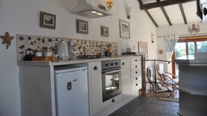 A kitchen with a built-in oven, a refrigerator, and a stove. There are framed pictures on the wall and a ceiling fan. - Converted stables - double studio 8km Obidos with elevated deck & full kitchen (Obidos)