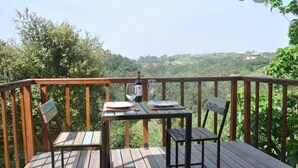 A wooden deck with a table and chairs, a bottle of wine, and a glass on the table. - Converted stables - double studio 8km Obidos with elevated deck & full kitchen (Obidos)