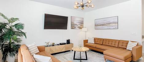 En moderne stue med sofasæt, sofabord, fjernsyn og billedkunst på væggene.