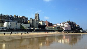 A coastal town with historic buildings, a prominent church tower, and a sandy beach.