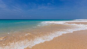 Une plage à l’eau turquoise et limpide, bordée d’un rivage sablonneux.