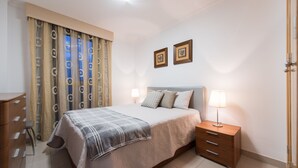 A bedroom with a bed, bedside tables, a dresser, and curtains.