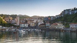 Une ville côtière dotée d’un port de plaisance, de bâtiments le long du front de mer et d’un paysage vallonné en arrière-plan.