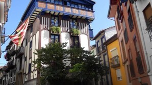 Un bâtiment doté d’un style architectural unique, caractérisé par une façade bleue et blanche remarquable, agrémentée de balcons et de plantes en pot.