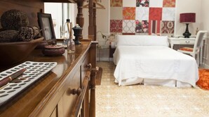 Une chambre à coucher avec un lit, une commode en bois et un mur orné d’une courtepointe.