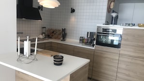 Une cuisine moderne avec des carreaux blancs, des armoires en bois, un four encastré et un plan de travail blanc.