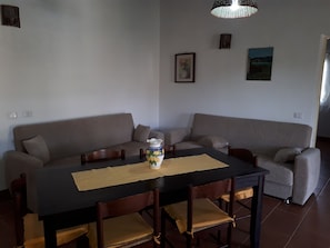 Un coin repas comprenant une table rectangulaire, quatre chaises en bois, un vase orné de motifs floraux et un set de table beige.