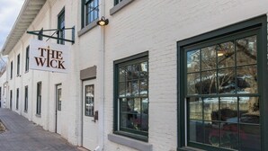 A white building with large windows and a sign that reads "The Wick".