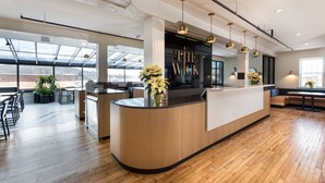 A modern reception area with a wooden reception desk, large windows, and a view of the cityscape.