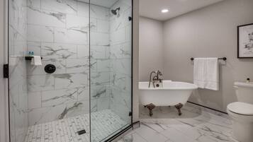 A modern bathroom with a glass-enclosed shower, a freestanding bathtub, and a toilet.