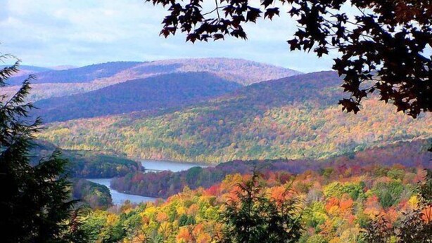 A mountainous landscape with autumn foliage and a river.