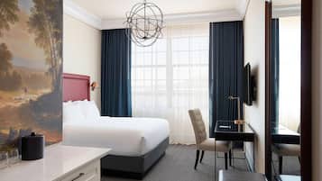 A hotel room with a large bed, a desk, a chair, a television, and a painting on the wall.