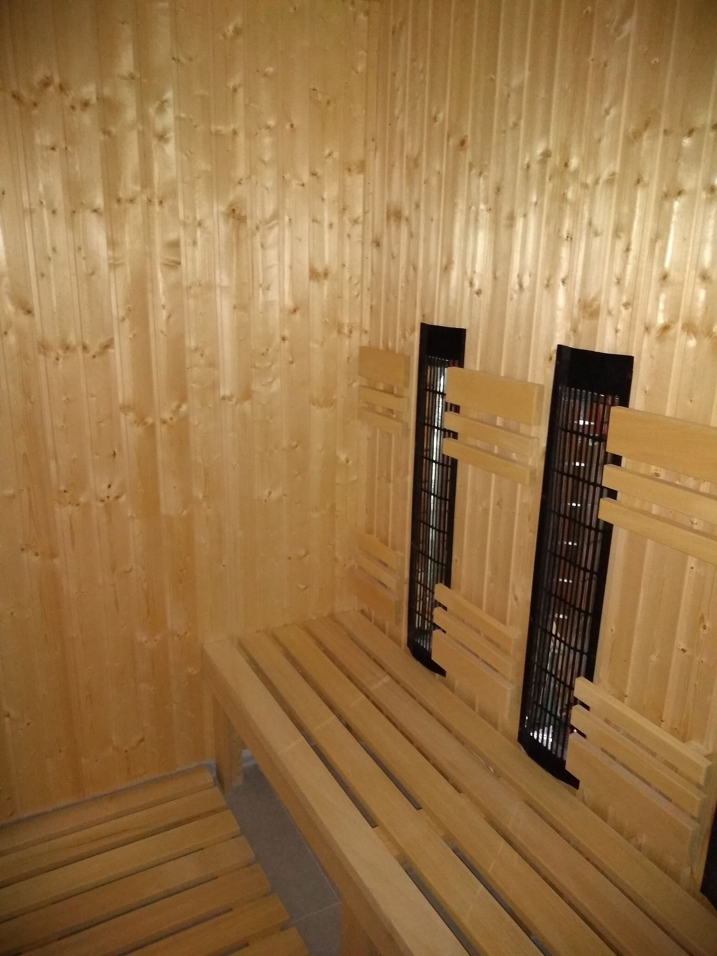 A wooden sauna with benches and a metal door.
