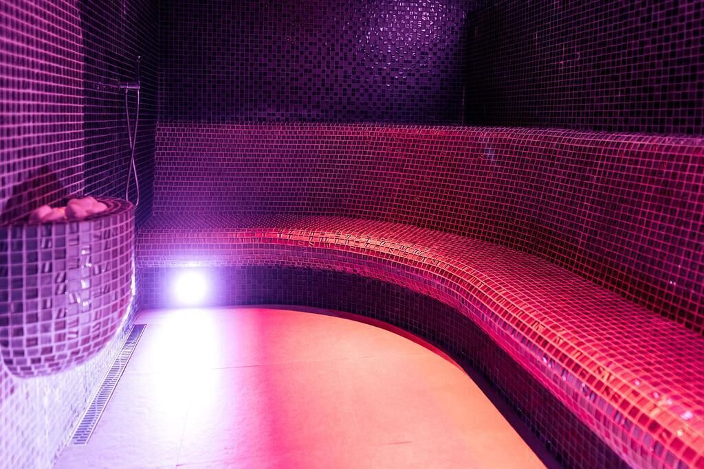 A spa room with a curved bench and a small seating area with a bowl of fruits.