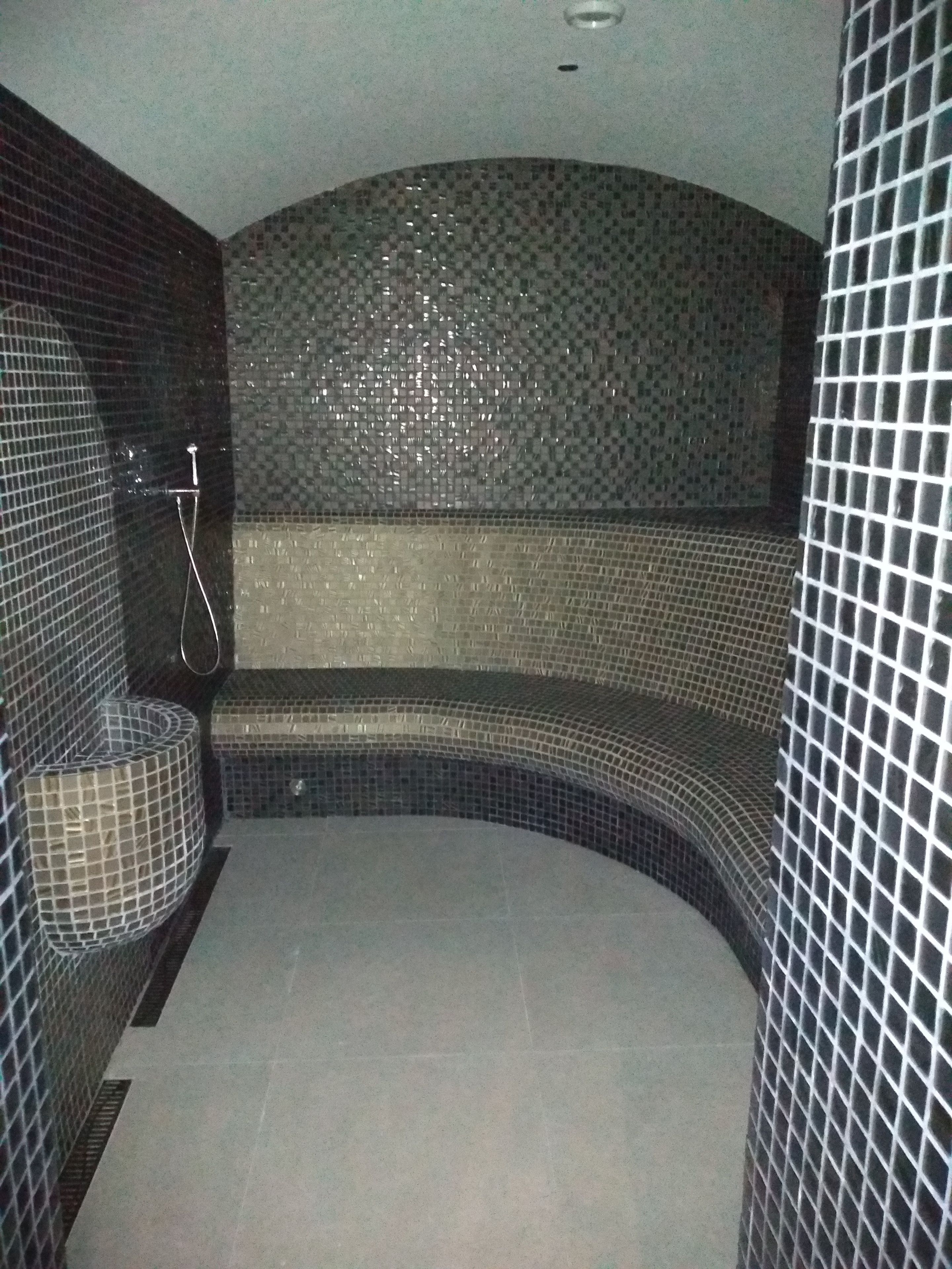Une salle de bain avec un banc incurvé, des murs carrelés et un espace douche.