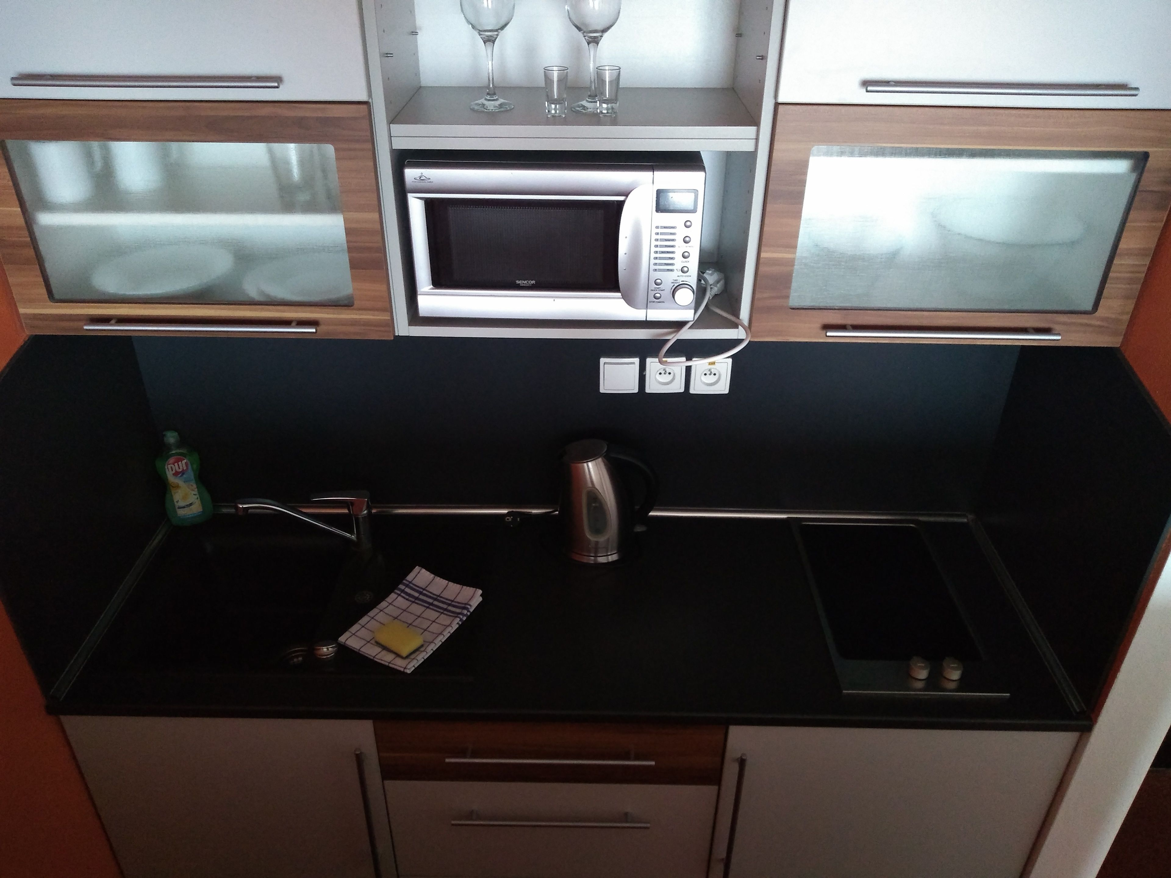 A compact kitchenette with a microwave, kettle, and a small countertop.