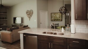 A kitchen with a marble countertop, stainless steel sink, and dark wooden cabinets. - Beautiful Lakeside Penthouse Award Winning Resort Just Minutes to Disney! (Kissimmee)