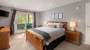 A bedroom with a bed, bedside tables, a TV, and a sliding glass door to a balcony. - Great place to stay for multiple families all year (Bartlett)