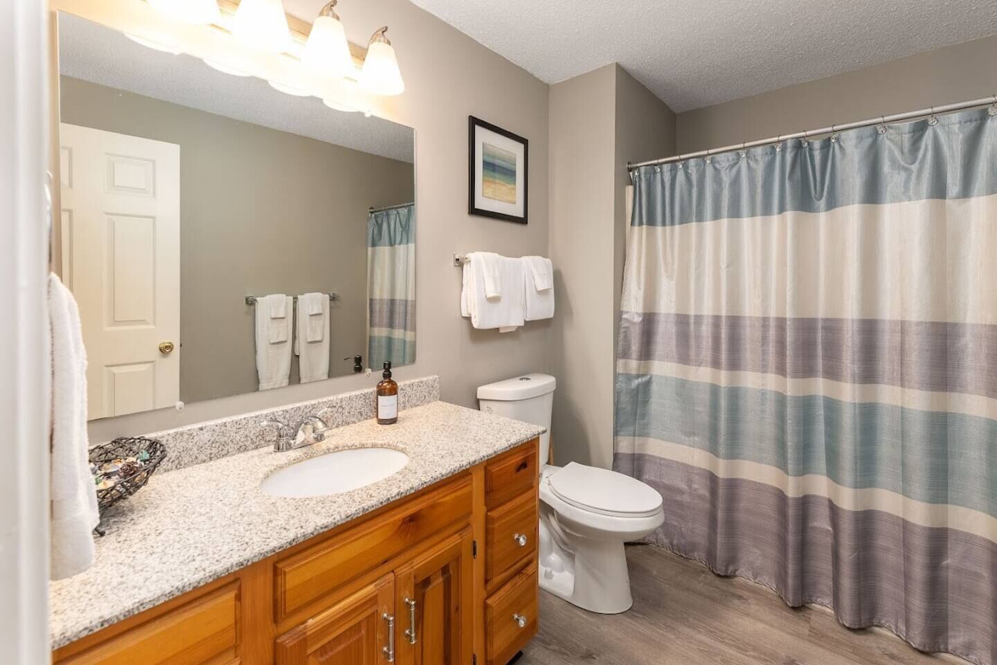 Une salle de bain avec un meuble-lavabo à deux vasques, des toilettes, un rideau de douche et un grand miroir.