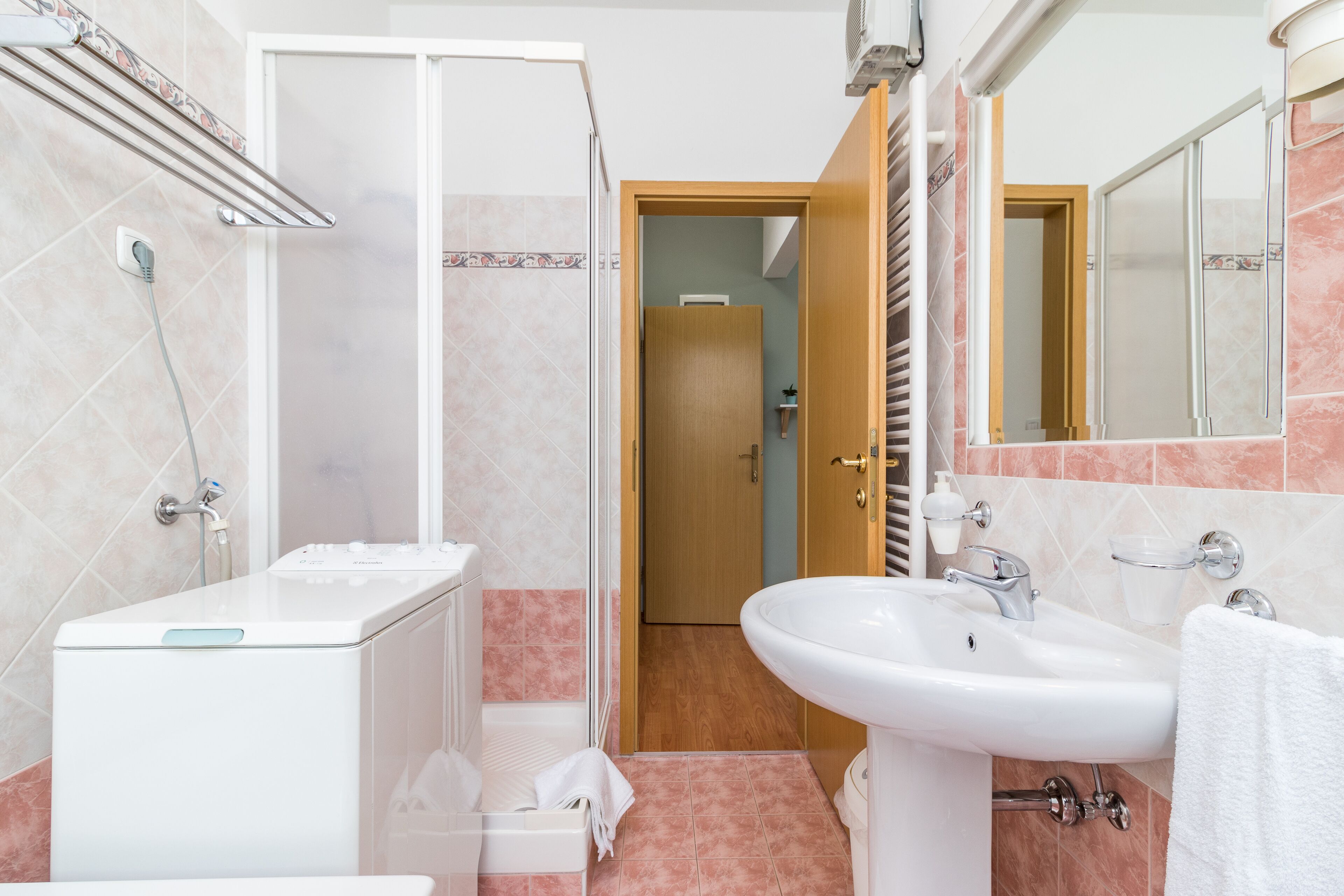Une salle de bain avec des toilettes blanches, un lavabo et une douche.