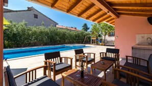 Zona d'seients exterior de fusta amb una piscina al fons.