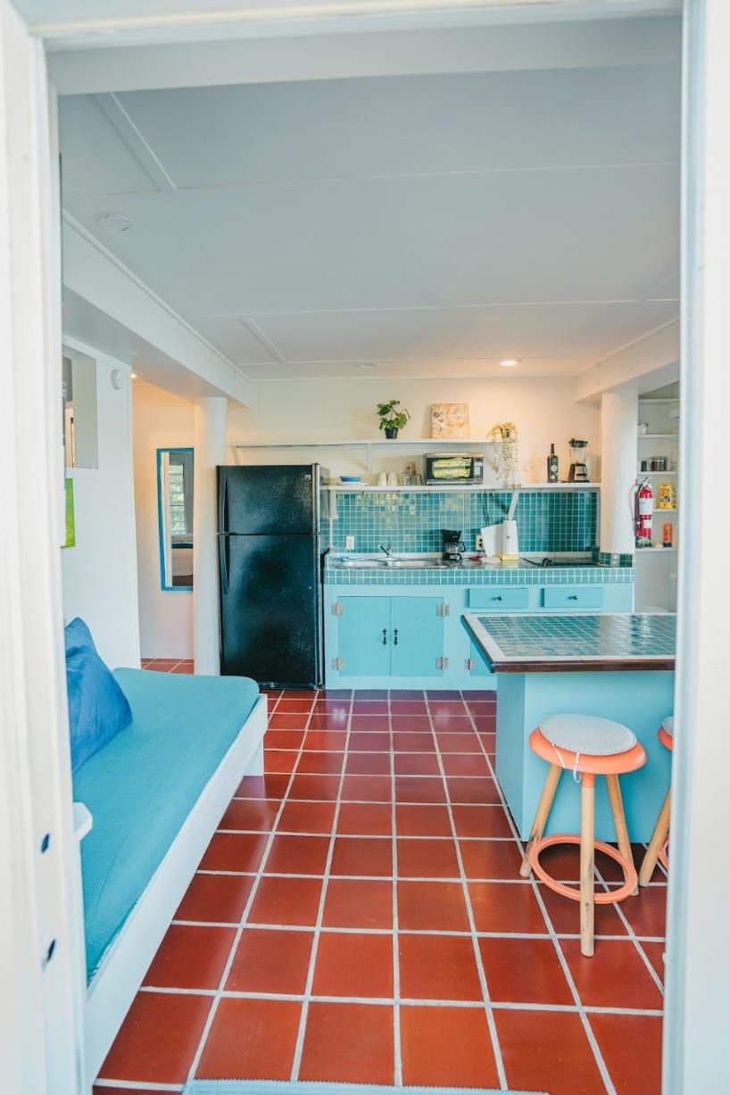 A compact kitchen with a refrigerator, a sink, and a tiled backsplash.