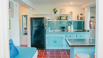 A compact kitchen with a refrigerator, a sink, and a tiled backsplash.