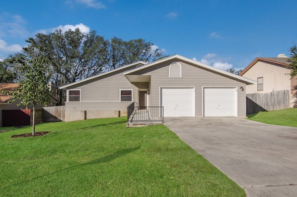 A single-story house with a garage, a small front yard, and a wooden fence.