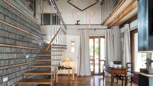 A staircase with stone steps and wooden handrails, leading to a room with a wooden floor, a table with a lamp, and a view through a glass door. - Luxury villa with pool on the slopes of Etna (Nicolosi)
