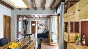 A spacious living area with a wooden dining table, a sofa, and a large window. - Luxury villa with pool on the slopes of Etna (Nicolosi)