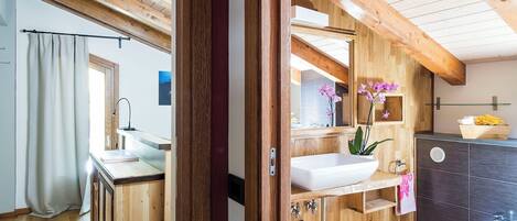 A wooden interior with a wooden ceiling, a white sink, a bidet, and a mirror.