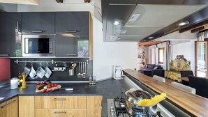 A modern kitchen with a gas stove, a microwave, and wooden cabinets. - Luxury villa with pool on the slopes of Etna (Nicolosi)