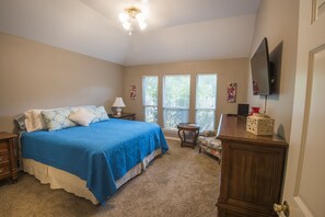 A bedroom with a bed, a nightstand, a dresser, a chair, a lamp, a television, and a window with blinds. - Great Location! Only 5-10 minutes from Kyle Field! (Bryan)