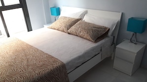 Un lit bien fait, avec une literie à motifs, une table de chevet avec une lampe et une petite table de nuit.