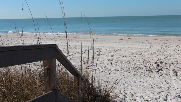 Een strand met een houten looppad dat naar het water leidt.