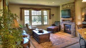 Ein Wohnzimmer mit Kamin aus Stein, bequemen Sitzgelegenheiten und einem Fernseher.