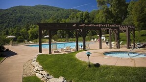 Ein Poolbereich mit einer Pergola, Liegestühlen und einem kleinen Pool.