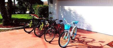Uma garagem com porta de número 5302, uma bicicleta com cesto azul e outra bicicleta vermelha encostada na parede.