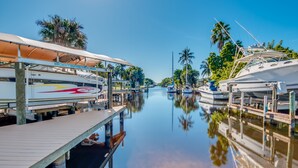 A marina with boats docked, wooden walkways, and palm trees. - BOATERS.HOUSE  South Florida Ranch in Cape Coral, Florida (Cape Coral)