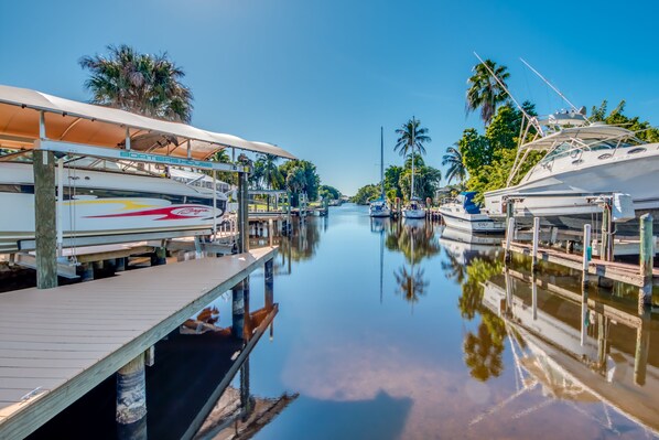 A marina with boats docked, wooden walkways, and palm trees.
