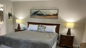 A bedroom with a large bed, two bedside tables, a nightstand, a painting on the wall, and a mirror. - Newly Updated, 2 King Beds, Pools, Hot Tub & Golf Course Views! Feels like home! (Branson)