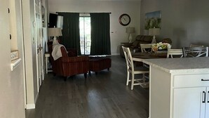 A spacious living area with a dining table and chairs, a sofa, and a kitchen area with a countertop. - Newly Updated, 2 King Beds, Pools, Hot Tub & Golf Course Views! Feels like home! (Branson)