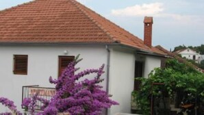 A white building with a red-tiled roof, a chimney, and a small window with shutters. - Apartment in garden 400m from the sea (Jelsa)