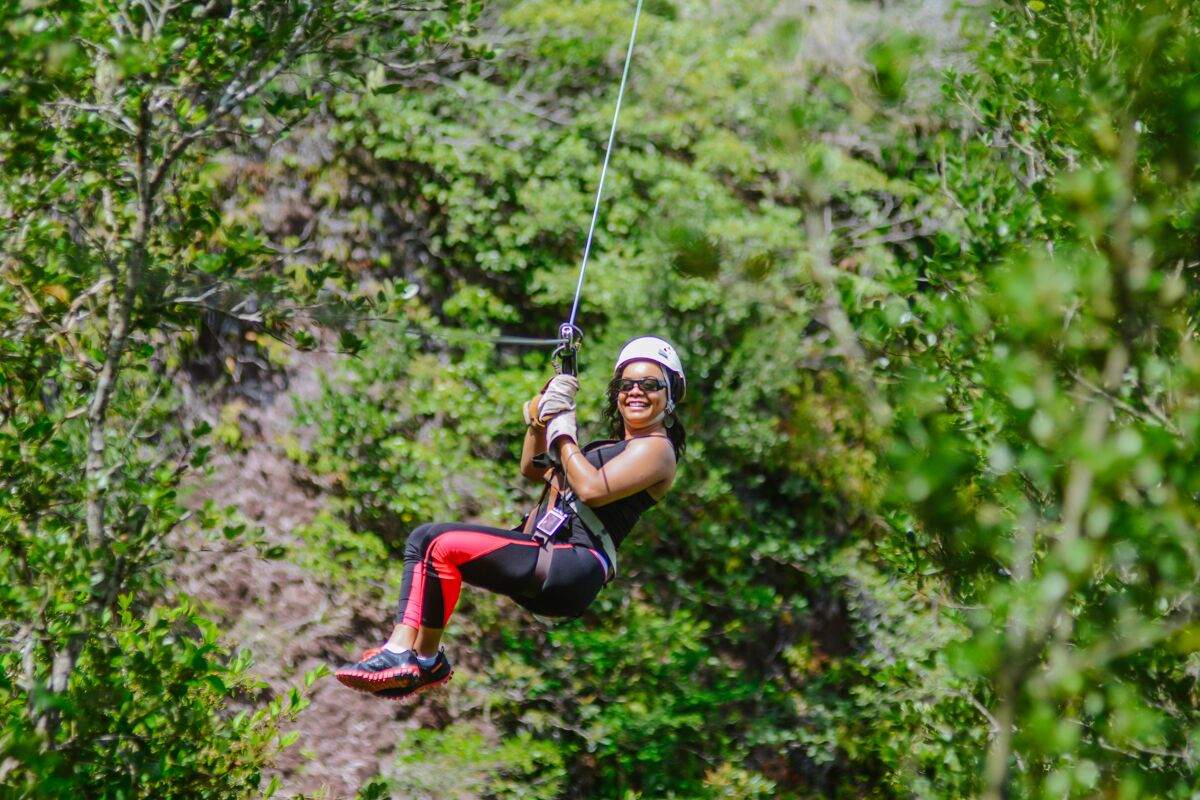 Una persona haciendo tirolesa por un área boscosa.