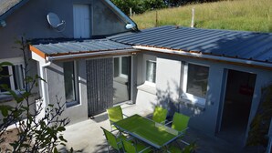 A small house with a metal roof, a satellite dish, and a patio with a table and chairs. - Comfortable cottages in Auvergne 4-6 people (Espinchal)