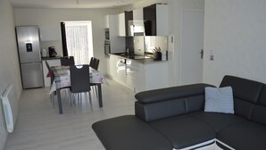 A modern kitchen with a refrigerator, stove, and dining area with a table and chairs. - Comfortable cottages in Auvergne 4-6 people (Espinchal)