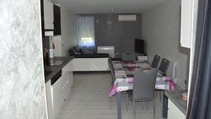 A compact kitchen with a dining area, a built-in oven, and a window with curtains. - Comfortable cottages in Auvergne 4-6 people (Espinchal)